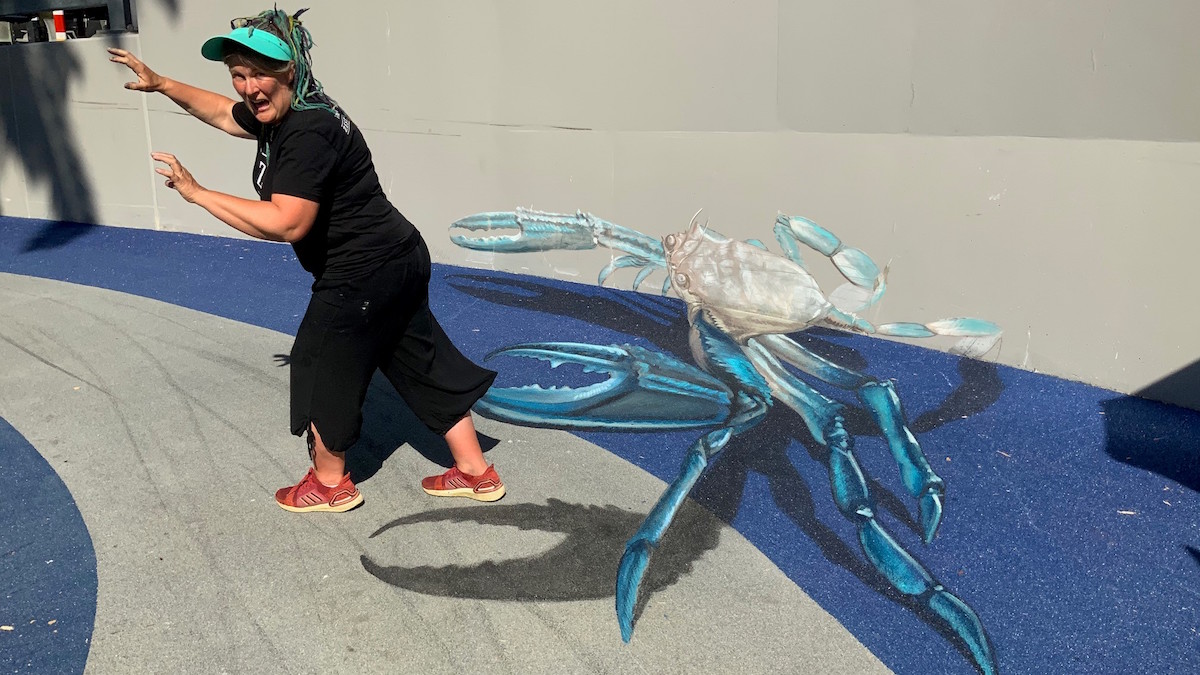 Woman next to blue crab mural
